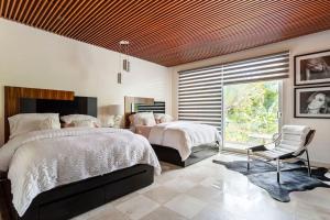 Un dormitorio con dos camas y una silla y una ventana. en CASA YOLO - Luxury 4 BR Comfort, Elegance at the paradise in Playacar!, en Playa del Carmen 38 fotos más
