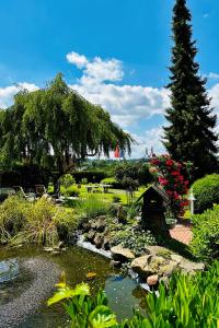 a garden with a pond and a pine tree at Landhotel Bellevue in Marburg an der Lahn