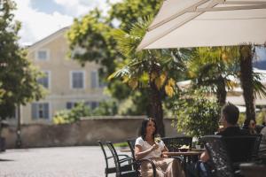 a woman sitting at a table under an umbrella at Residence Chiavi D'Oro - Goldener Schl&uuml;ssel in Bressanone