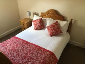 a bed with red and white pillows on it at Belton House Holiday Home in Wanlockhead