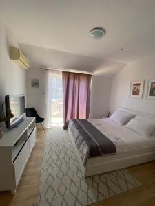 a bedroom with a large bed and a television at Apartman Dubravka 1 in Orebić