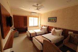 a hotel room with two beds and a tv at The Hotel SAAJ-Premium in Bhubaneshwar