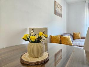 a vase with yellow flowers on a table in a living room at Luča apartman in Podgorica