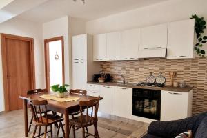 a kitchen with white cabinets and a table with chairs at Bella Piana Home in Brolo +13 photos