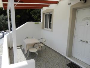 a white house with a table and chairs on a balcony at Villa Teozenia in Achladies