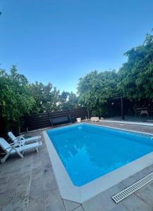 a swimming pool with two lounge chairs next to it at A Detached Floor in Parekklisha