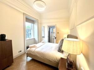 a bedroom with a bed with a lamp and a window at 'Mac' in ApartNest Auchterarder in Auchterarder