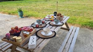 a picnic table with cups and plates of food on it at Relais équestre du Miloir - chambres d'hôtes in Saint-Désir