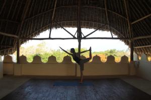 ディアニ・ビーチにあるLamu style one bedroom apartment, central Dianiの窓付きの部屋でヨガのポーズをしている女性