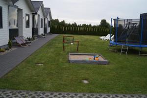 a yard with a playground with two swings at SŁONECZNE DOMKI in Gąski