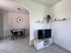 a living room with a tv and a table with chairs at La Noce Holiday House in Massa Lubrense