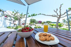 Un plato de galletas y un bol de fruta y un vaso de zumo. en Adagio Villas Kamari, en Kamari