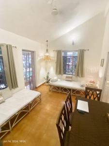 a living room with a couch and tables and windows at Beachside Apartment - Cozy By The Sea Goa in Panaji