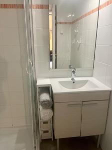 a white bathroom with a sink and a mirror at La plagiste in Saint-Palais-sur-Mer