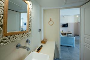 un baño con espejo y lavabo en Adagio Villas Kamari, en Kamari 159 fotos más