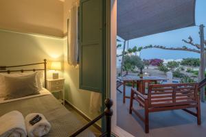 Un dormitorio con una cama y un balcón con una mesa. en Adagio Villas Kamari, en Kamari