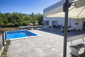 Un patio con piscina y sombrilla. en Apartment - CASA Adrianovo, en Ljubuški
