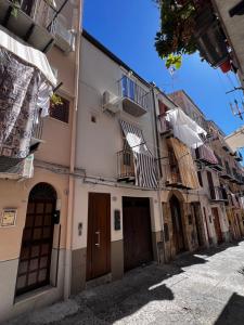 a street in an old building with clothes drying on a balcony at Renard Suite in Cefalù
