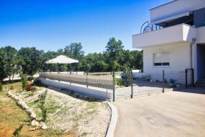 una casa blanca con una valla y una sombrilla en Apartment - CASA Adrianovo, en Ljubuški