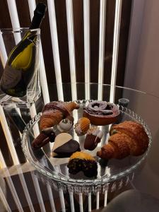 a glass plate with pastries on a table with a bottle of wine at Renard Suite in Cefalù