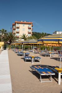 a row of picnic tables and umbrellas on a beach at Hotel Eden in Grottammare
