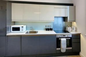 a kitchen with white cabinets and a sink and a microwave at City view luxury by BSE Homes in Chelmsford +9 photos