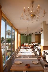 a dining room with tables and chairs and a chandelier at Hotel Eden in Grottammare