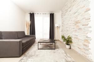 een woonkamer met een bank en een bakstenen muur bij New Apartment in Vrnjačka Banja