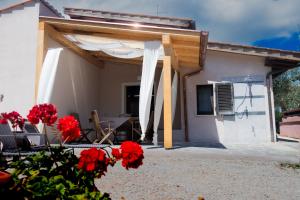 a patio with red flowers in front of a house at Villa il Poderino in Marina di Campo