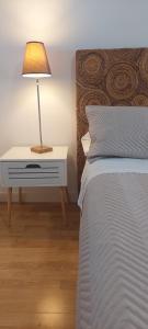 a bedroom with a bed and a lamp on a night stand at Amplio apartamento con terraza con vistas "Victoria Stay" in Alcalá la Real