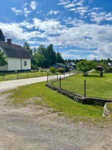 a road next to a white house with a fence at Vallvikshuset in Vallvik