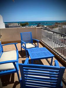 three blue chairs and tables on a balcony with the ocean at Casa Orsini Vista Mare -Manfredi Homes&Villas in Manfredonia