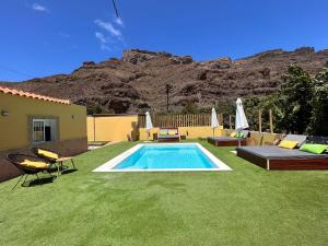 a backyard with a swimming pool and a grass yard at SUNNY CARMELITO DELUXE in Mogán