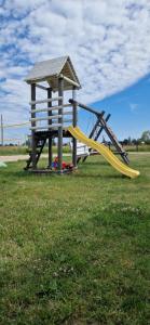a playground with a yellow slide in a park at Szary Domek Mikołajki in Mikołajki