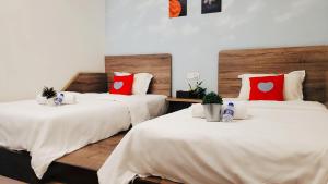 a bedroom with two beds with white sheets and red pillows at Winggarden Murals House by JE Boutique Guesthouse in Ipoh +44 photos