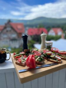 a wooden cutting board with bread and tomatoes on it at Apartament Villa Nelly in Szklarska Poręba