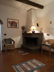 a living room with a fireplace with two chairs and a lamp at Casa Mirella in Castiglion Fiorentino