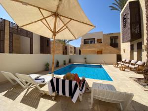 une piscine avec des chaises, un parasol et un ours en peluche dans l'établissement Nayah Stays, Amazing villa with private pool & 5 master suites, à Hurghada