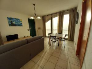 a living room with a couch and a table and chairs at Appartamento OttoArchi in Ferrere
