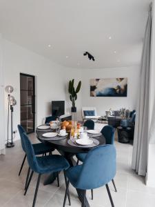 a living room with a table and blue chairs at Seaside Living - Apartment Stella in De Panne