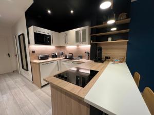 Una cocina con gabinetes blancos y una encimera negra. en Le Nid Havrais, en Le Havre