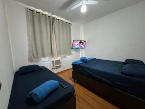 a bedroom with two beds and a flat screen tv at Hospedagem Canal do Bora Viajar in Rio de Janeiro