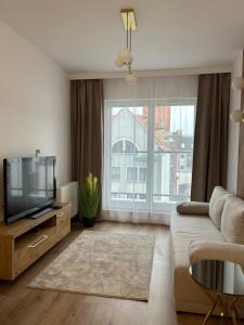 a living room with a tv and a large window at Apartament Stare Miasto in Elblag