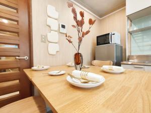 a wooden table with plates and flowers in a kitchen at 65 两室一厅 駒込站4分 近商业街 2 rooms 4 mins to ST Max 7P 直达新宿 涉谷 表参道 池袋 上野 代代木 银座 原宿 in Tokyo