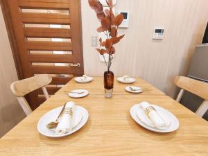 a wooden table with white plates and a vase with flowers at 65 两室一厅 駒込站4分 近商业街 2 rooms 4 mins to ST Max 7P 直达新宿 涉谷 表参道 池袋 上野 代代木 银座 原宿 in Tokyo