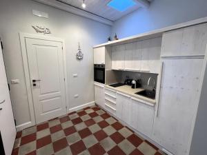 a kitchen with white cabinets and a checkered floor at Terrazza Nostromo Francesco in Trani +18 photos