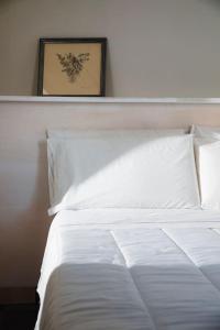 a bedroom with a white bed with a picture on the wall at Terrazza Nostromo Francesco in Trani +18 photos