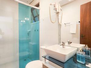 a bathroom with a sink and a glass shower at Saint Moritz 204 a 2 quadras da Rua Coberta in Gramado