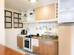 a kitchen with wooden cabinets and a stove top oven at Saint Moritz 204 a 2 quadras da Rua Coberta in Gramado