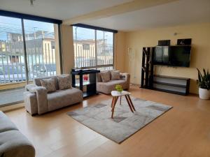 a living room with couches and a tv and a table at Spacious private rooms close to American Embassy in Quito